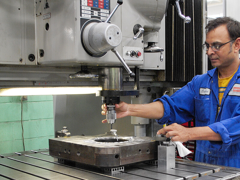 A machine operator on a jig boring machine aligns a work piece to the table of the machine