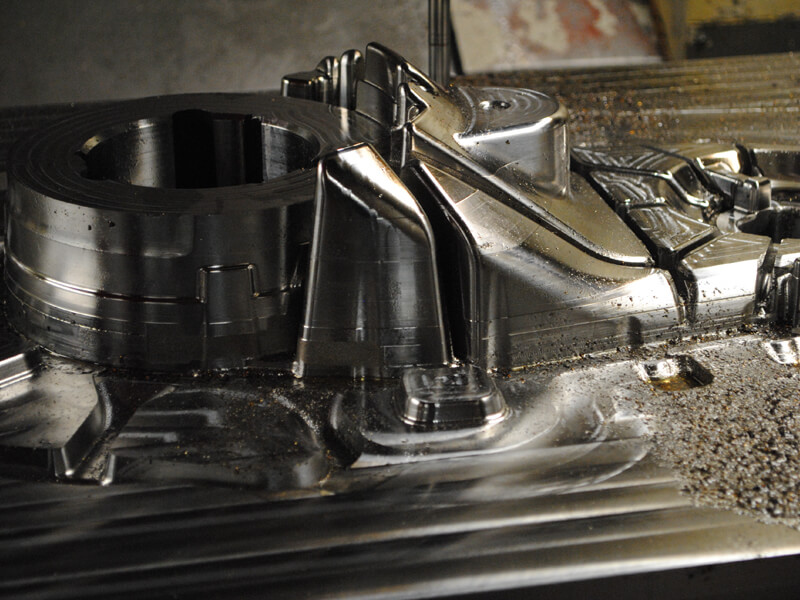 Screen shows a high pressue die cast mould insert being machined on a vertical CNC machine